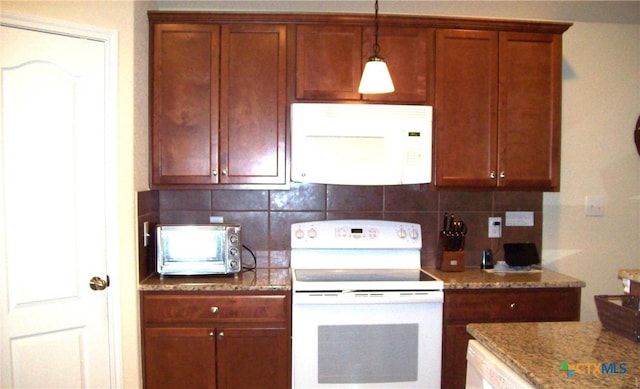 kitchen featuring tasteful backsplash, white appliances, light stone countertops, and decorative light fixtures