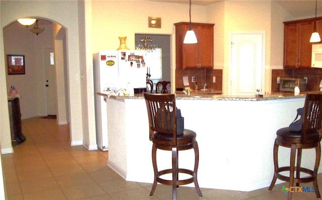 kitchen featuring backsplash, white appliances, and decorative light fixtures