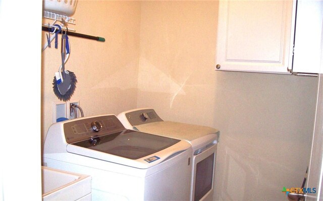 laundry area with cabinets, washing machine and dryer, and sink