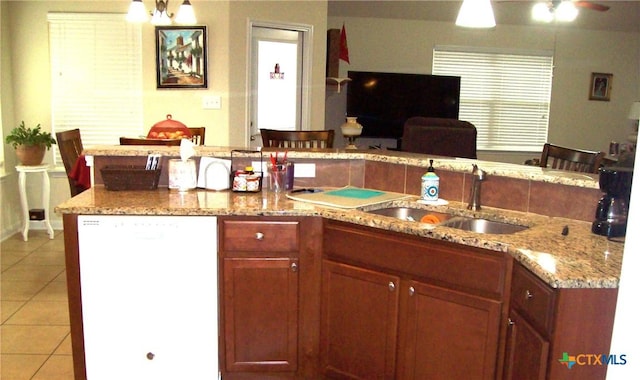 kitchen featuring sink, light tile patterned floors, a breakfast bar, ceiling fan, and white dishwasher