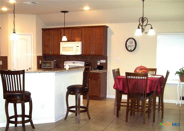 kitchen featuring stove, decorative light fixtures, decorative backsplash, and stone counters