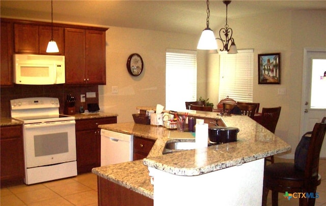 kitchen featuring a kitchen bar, kitchen peninsula, pendant lighting, white appliances, and light stone countertops