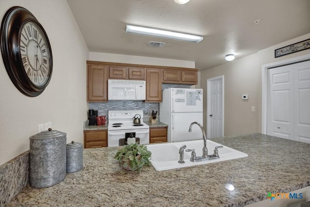 730 E Mather St Unit B101, New Braunfels, TX 78130 - kitchen featuring white appliances, tasteful backsplash, a peninsula, brown cabinetry, and light stone counters