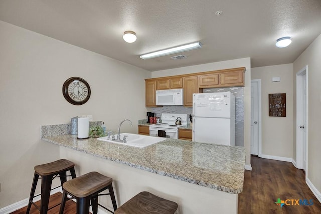 730 E Mather St Unit B101, New Braunfels, TX 78130 - kitchen featuring white appliances, a peninsula, a breakfast bar area, dark wood-style flooring, and a textured ceiling