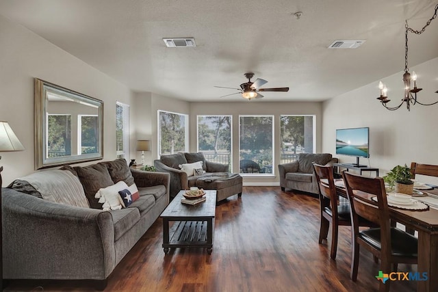 living room with dark hardwood / wood-style flooring and ceiling fan with notable chandelier