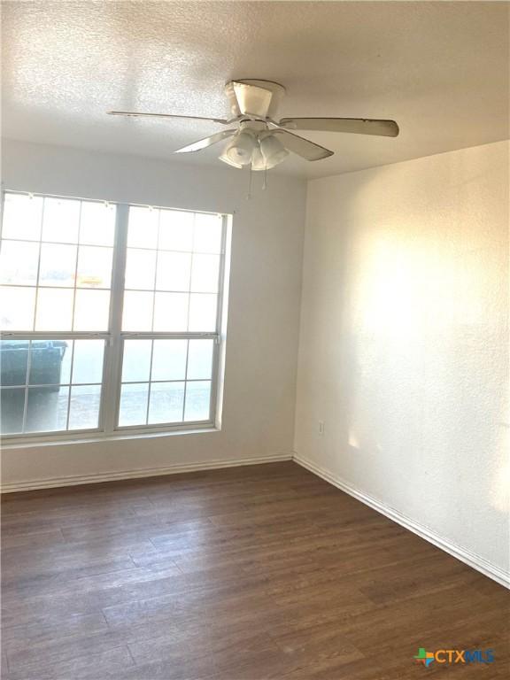 spare room with ceiling fan, dark hardwood / wood-style flooring, and a textured ceiling