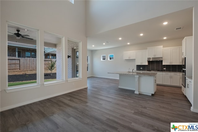 kitchen with a kitchen island with sink, appliances with stainless steel finishes, white cabinetry, and wood-type flooring