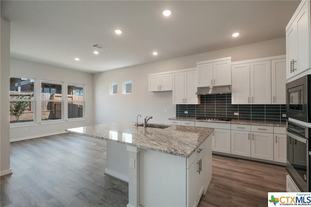 2240 Sur Ave, New Braunfels, TX 78132 - kitchen with black appliances, a sink, under cabinet range hood, dark wood finished floors, and decorative backsplash