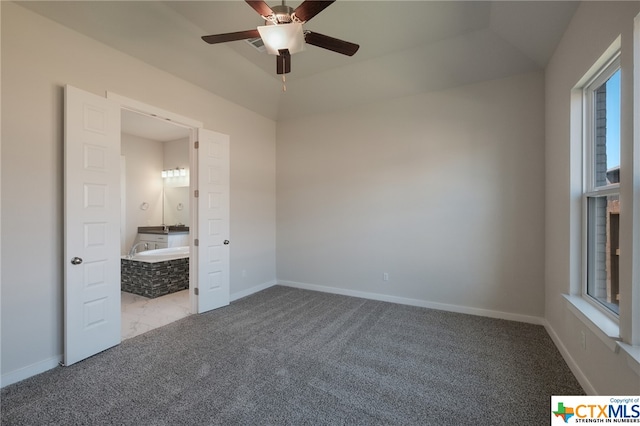 unfurnished bedroom featuring light colored carpet, ceiling fan, and ensuite bath