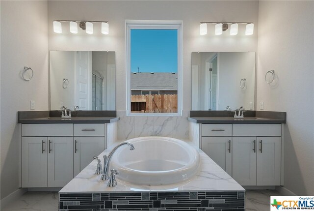 2240 Sur Ave, New Braunfels, TX 78132 - full bathroom with marble look tiles, a bath, two vanities, a shower, and baseboards