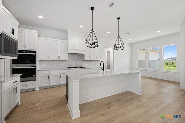 kitchen featuring white cabinets, light hardwood / wood-style flooring, a center island with sink, and custom exhaust hood