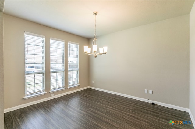 unfurnished room featuring dark wood-type flooring and an inviting chandelier