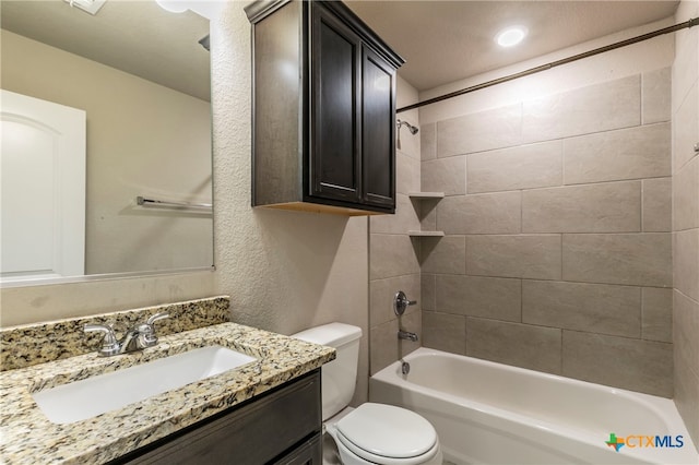 full bathroom with toilet, tiled shower / bath combo, and vanity