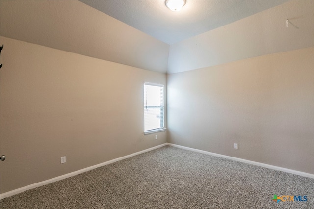 spare room with carpet flooring and vaulted ceiling