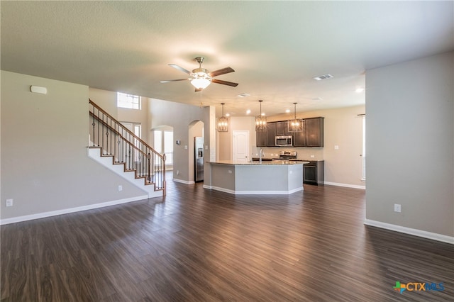 unfurnished living room featuring dark wood-type flooring, ceiling fan, a textured ceiling, and sink