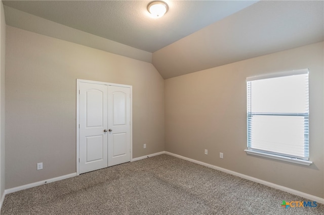 spare room featuring vaulted ceiling and carpet