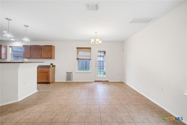 8913 Winter Haven Rd, Austin, TX 78747 - kitchen featuring a chandelier, decorative light fixtures, light tile patterned floors, brown cabinetry, and baseboards