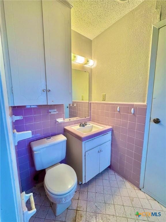 1804 Prather Dr, Killeen, TX 76541 - half bathroom featuring a textured ceiling, tile walls, vanity, toilet, and a textured wall