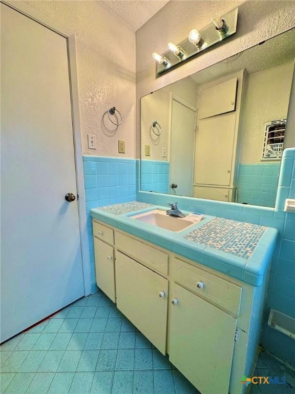 1804 Prather Dr, Killeen, TX 76541 - bathroom with a textured ceiling, tile walls, wainscoting, vanity, and tile patterned floors