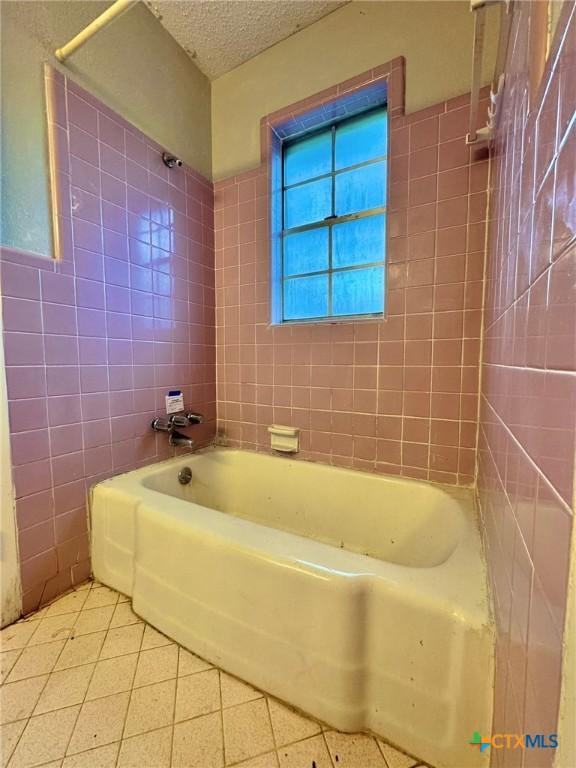 1804 Prather Dr, Killeen, TX 76541 - bathroom with a textured ceiling, tile patterned floors, tile walls, and shower / tub combination