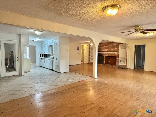 1804 Prather Dr, Killeen, TX 76541 - unfurnished living room featuring light wood-style flooring, a textured ceiling, arched walkways, and ceiling fan