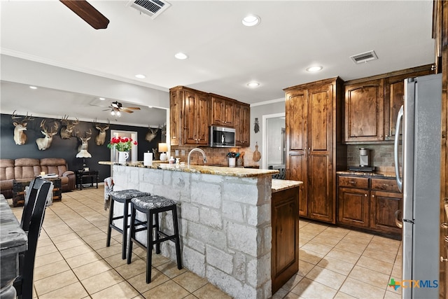 kitchen featuring light tile patterned flooring, crown molding, appliances with stainless steel finishes, and tasteful backsplash