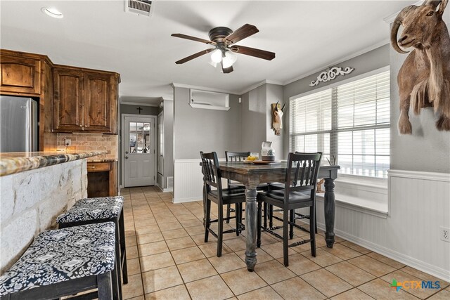 tiled dining room with ceiling fan and crown molding