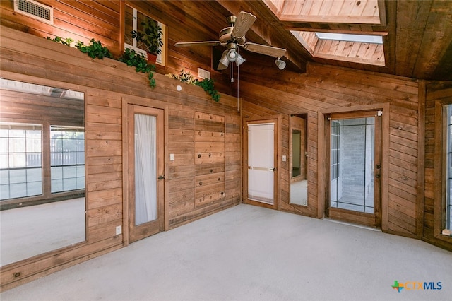 interior space featuring wood walls, ceiling fan, wood ceiling, and lofted ceiling with skylight