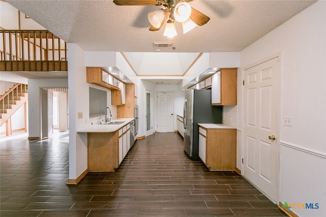 kitchen with stainless steel appliances, sink, ceiling fan, a textured ceiling, and dark wood-type flooring