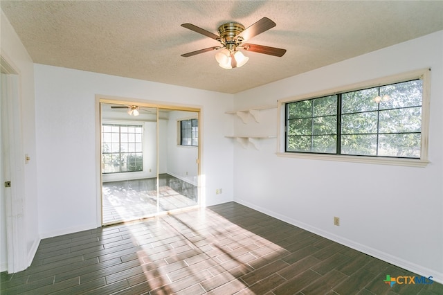 empty room with dark hardwood / wood-style flooring, a textured ceiling, and ceiling fan