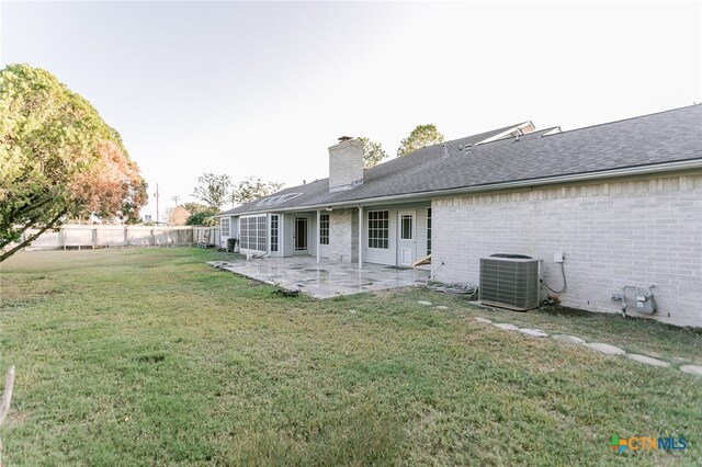 back of property featuring central AC unit, a patio, and a lawn