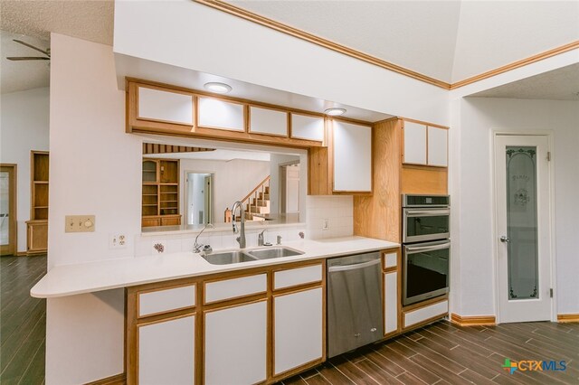 kitchen featuring dark wood-type flooring, white cabinets, kitchen peninsula, sink, and appliances with stainless steel finishes