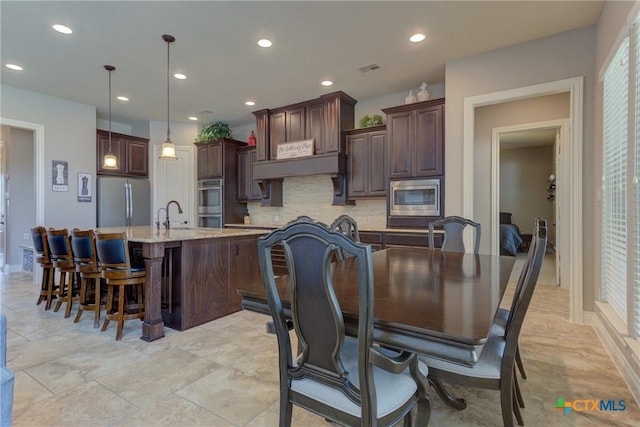 2326 Haven Bluff Ct, New Braunfels, TX 78132 - kitchen featuring stainless steel appliances, tasteful backsplash, dark brown cabinets, a kitchen island with sink, and a kitchen bar