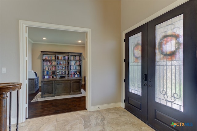 foyer featuring light wood-type flooring, french doors, and crown molding