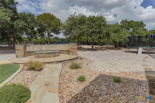 2326 Haven Bluff Ct, New Braunfels, TX 78132 - view of yard featuring a trampoline, a patio, a fire pit, and fence