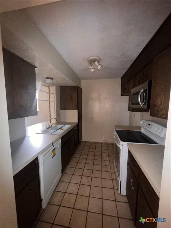 kitchen with sink, a textured ceiling, white appliances, dark brown cabinets, and light tile patterned floors