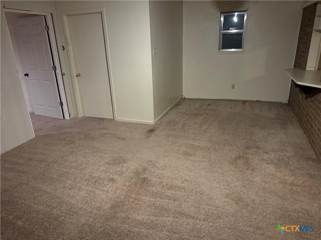 carpeted spare room featuring brick wall