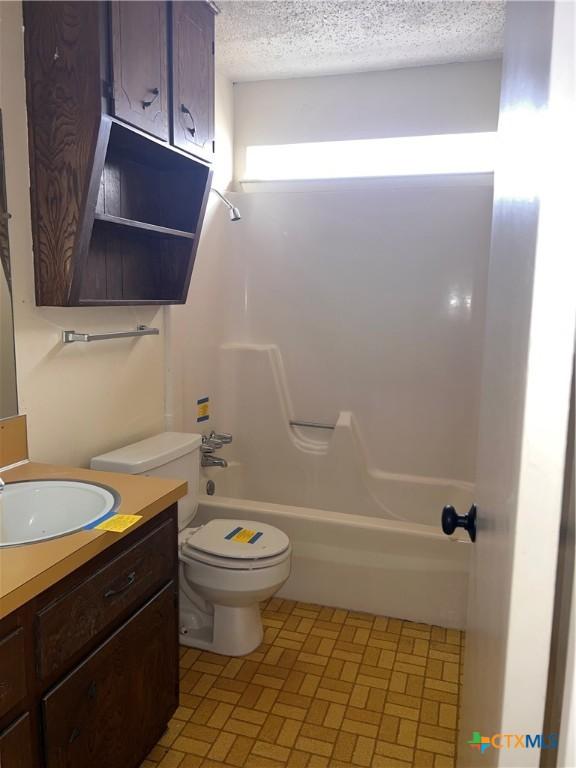 full bathroom featuring vanity, shower / bath combination, a textured ceiling, and toilet