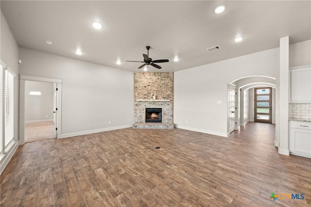 6119 Big Tree Dr, Salado, TX 76571 - unfurnished living room with arched walkways, wood finished floors, a ceiling fan, recessed lighting, and a fireplace