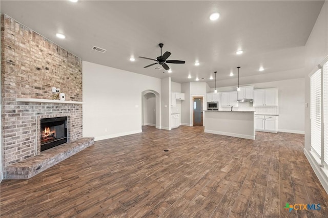 6119 Big Tree Dr, Salado, TX 76571 - unfurnished living room featuring ceiling fan, dark wood-style flooring, recessed lighting, a fireplace, and arched walkways