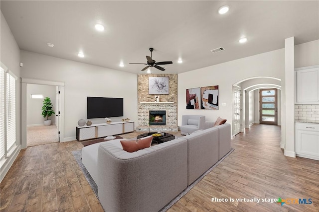 6119 Big Tree Dr, Salado, TX 76571 - living area with arched walkways, a ceiling fan, light wood finished floors, a brick fireplace, and recessed lighting