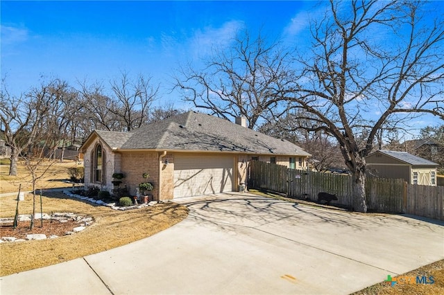 view of side of home with an attached garage, brick siding, fence, concrete driveway, and a chimney