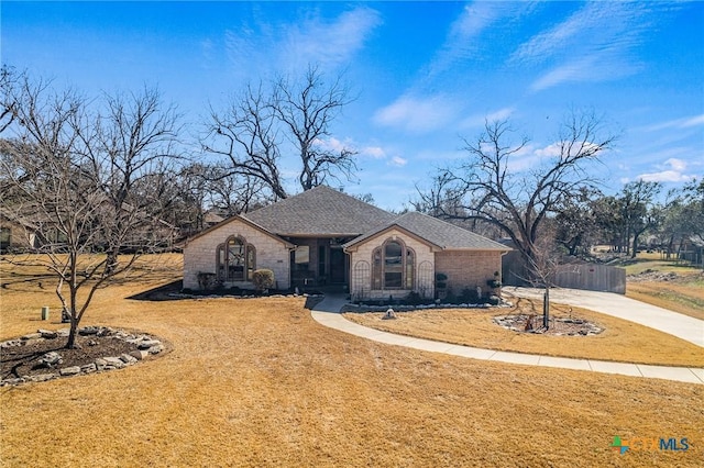 view of front of home with a shingled roof, a front yard, concrete driveway, and brick siding