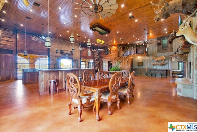 dining space with a high ceiling, wooden walls, and wooden ceiling