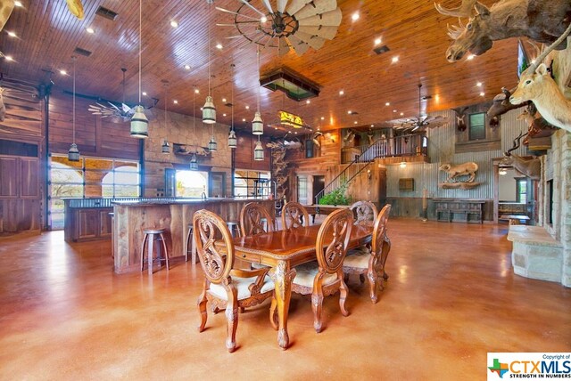 dining space with a high ceiling, wooden walls, and wooden ceiling