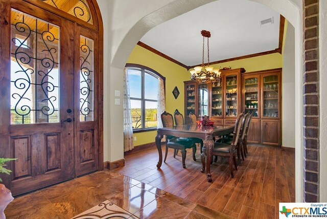 dining space featuring dark hardwood / wood-style floors, an inviting chandelier, and ornamental molding