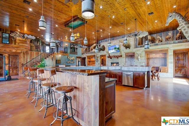 kitchen featuring a high ceiling, a kitchen bar, decorative light fixtures, and dishwasher