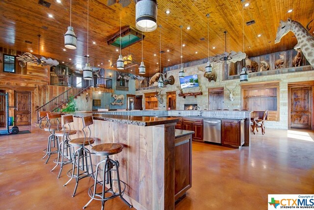 kitchen featuring a high ceiling, a kitchen bar, decorative light fixtures, and dishwasher