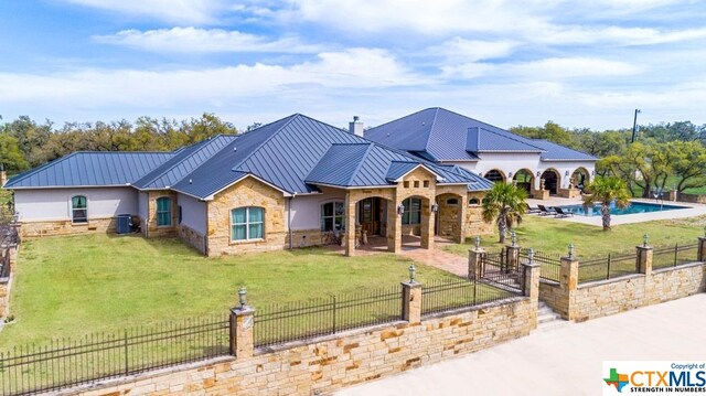 view of front of home with central AC unit, a front lawn, a patio, and a fenced in pool