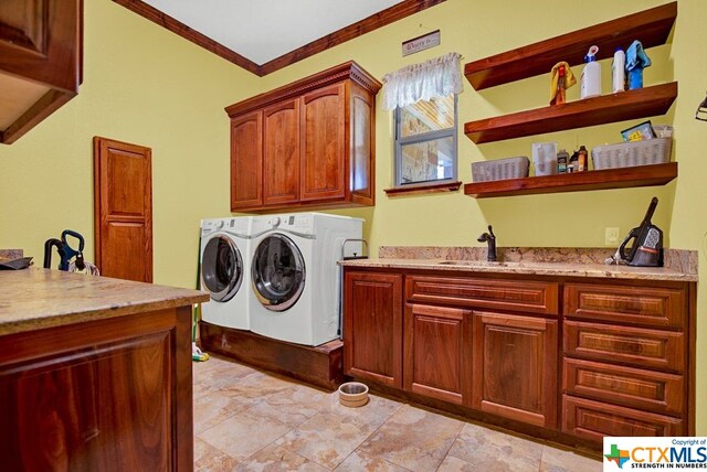 laundry room featuring washer and clothes dryer, cabinets, crown molding, and sink